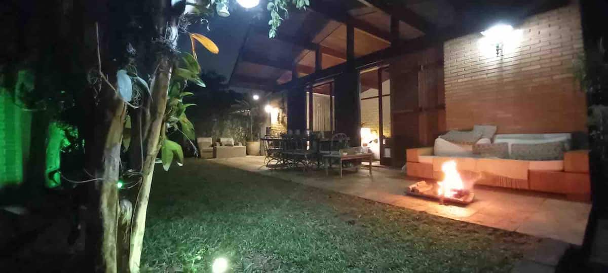Jardim a noite com fogueira e area coberta iluminada