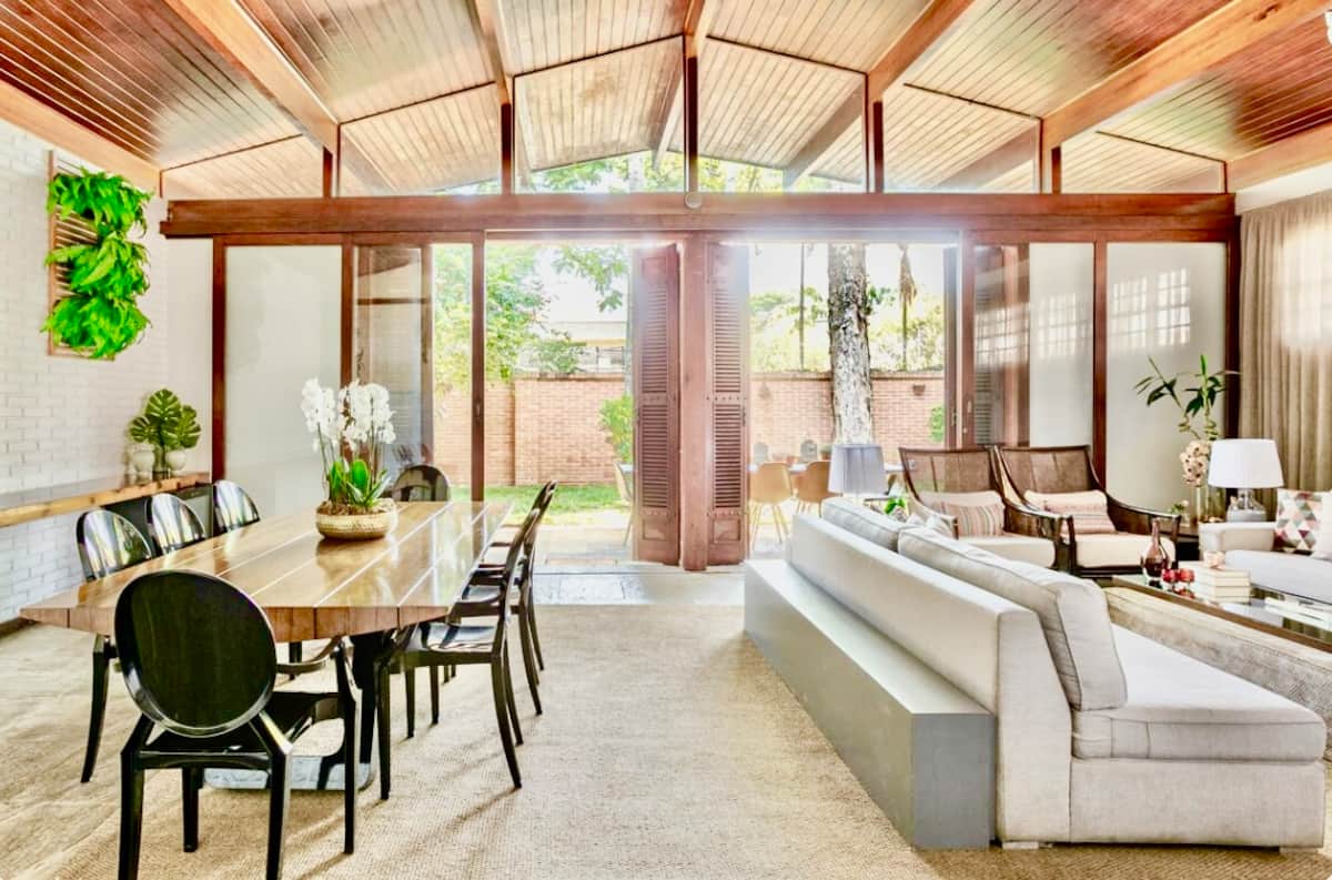 Sala de jantar com teto de madeira e portas para o jardim