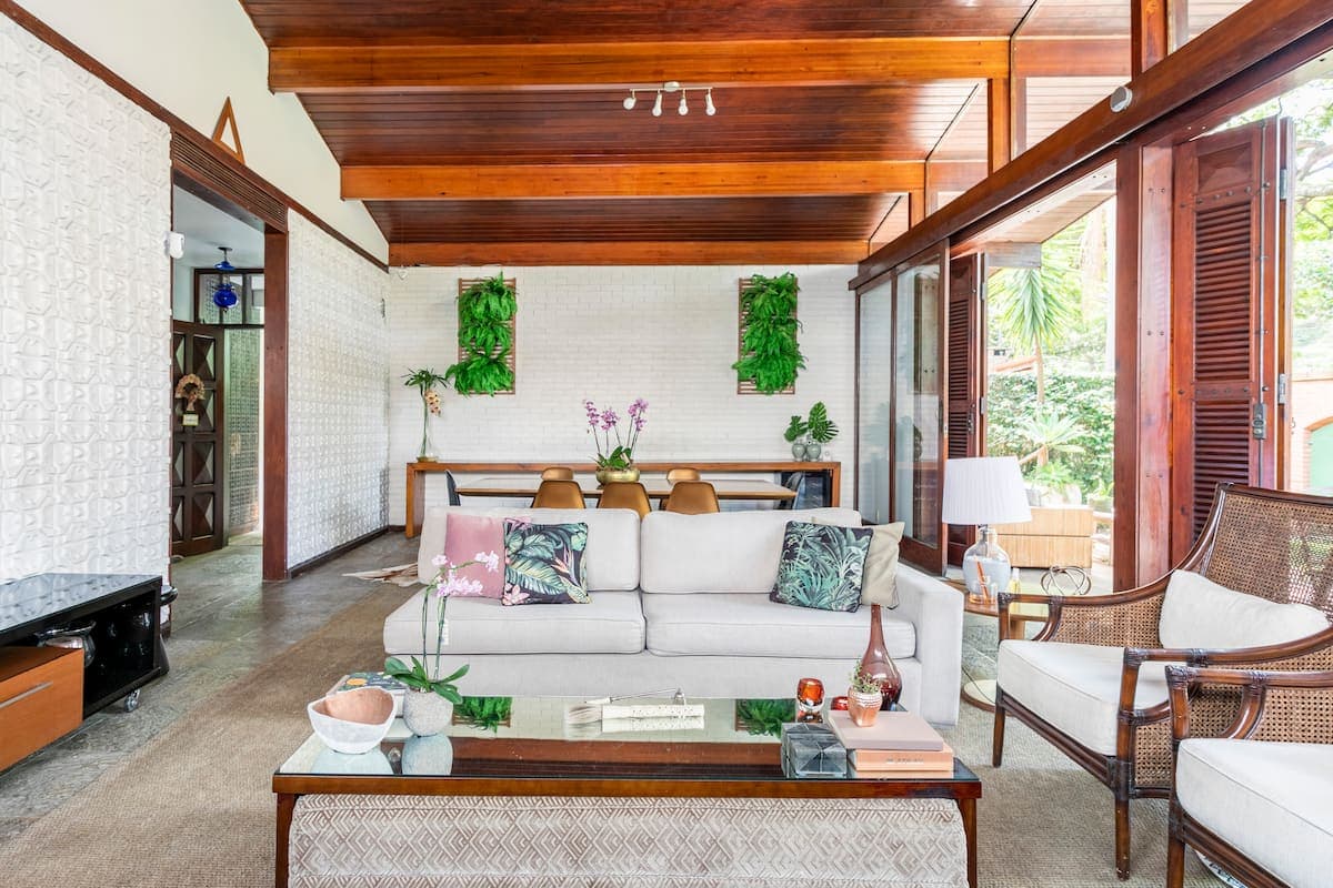Sala de estar com sofa claro e teto de madeira