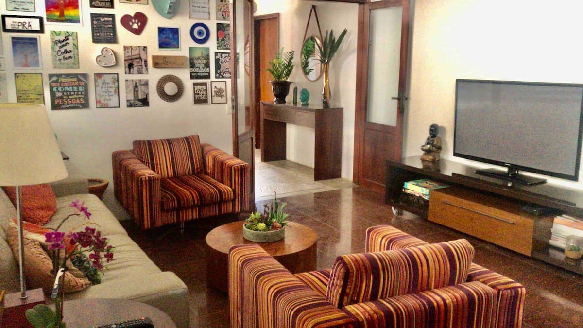 Sala de TV com poltronas listradas e parede de quadros