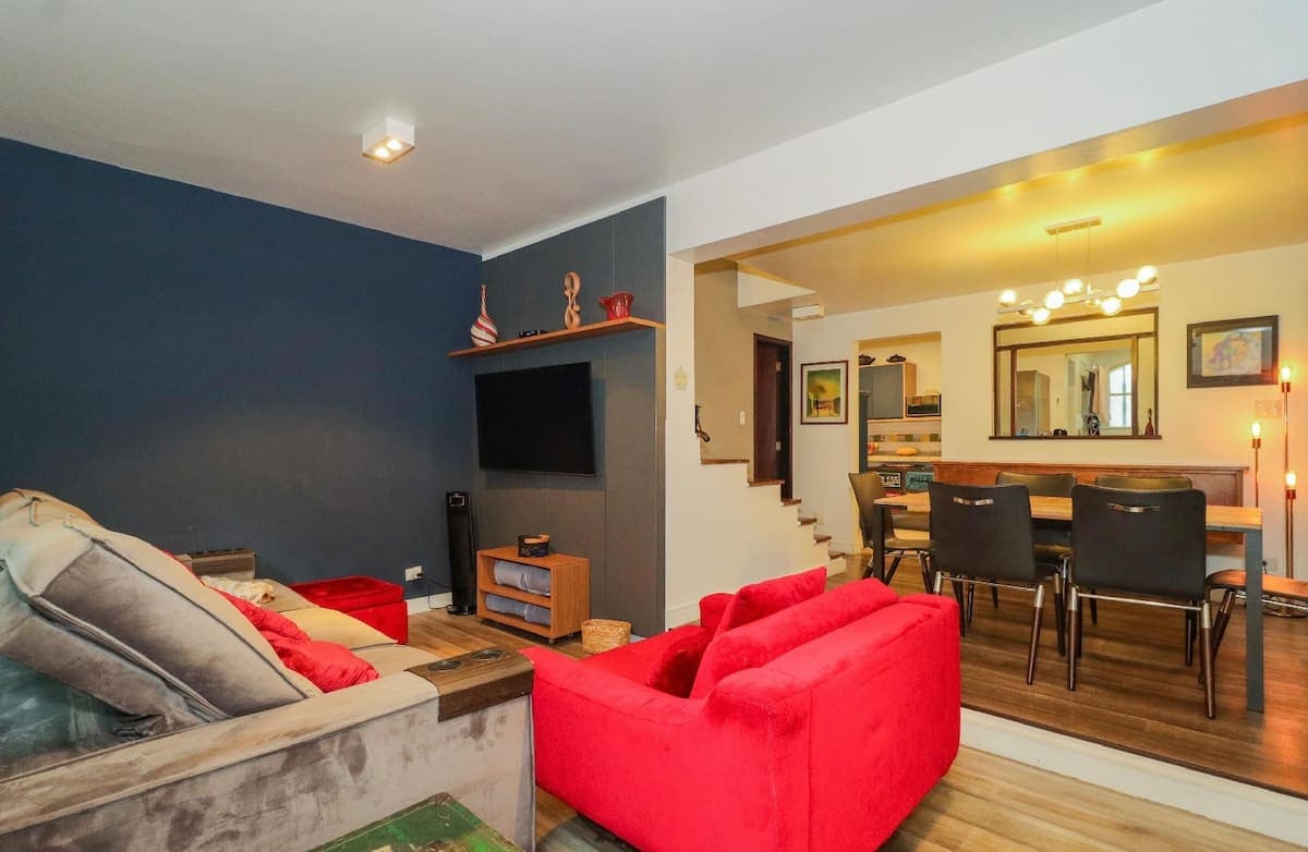 Sala de estar com sofá vermelho e mesa de jantar ao fundo
