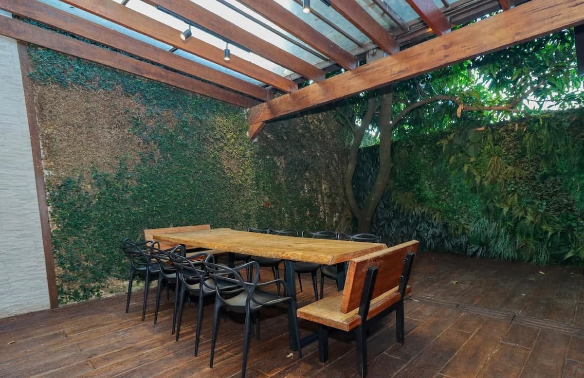 Mesa comprida sob cobertura de vidro ao lado do jardim vertical