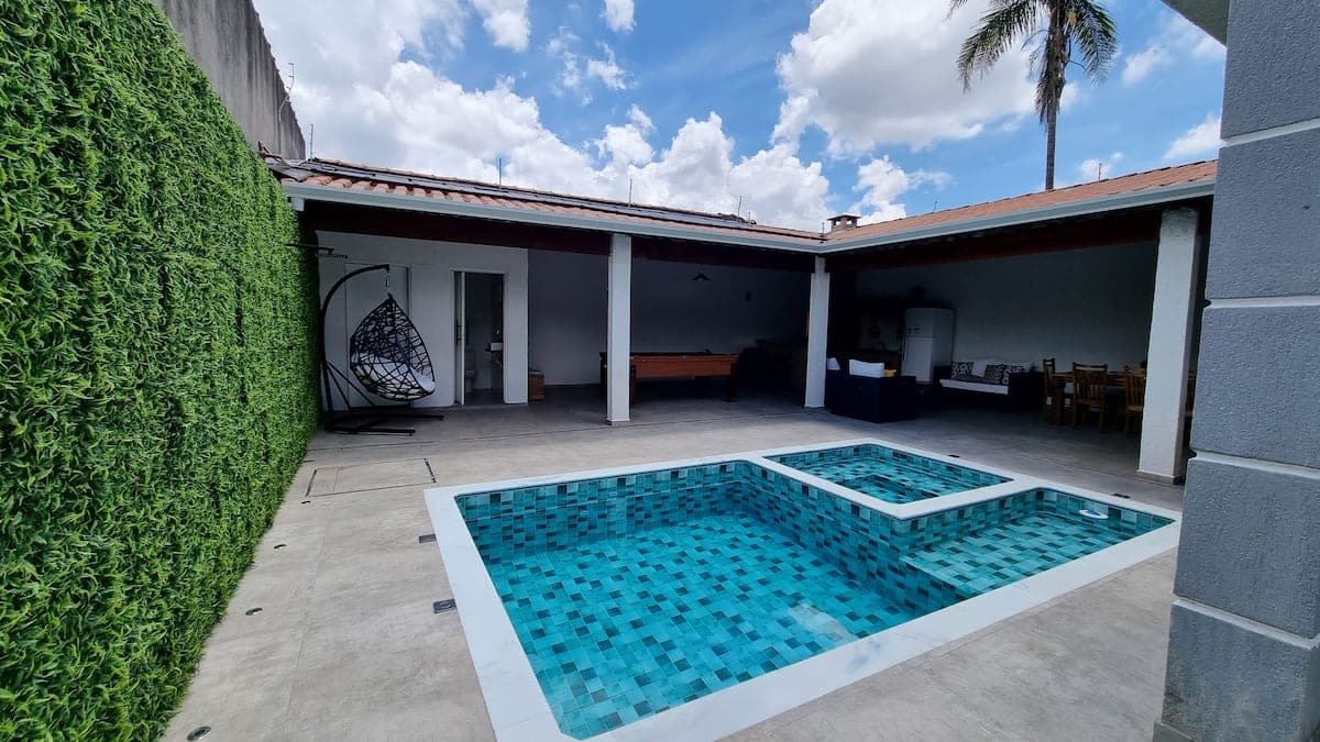 Quintal com piscina, muro de folhagem e area coberta