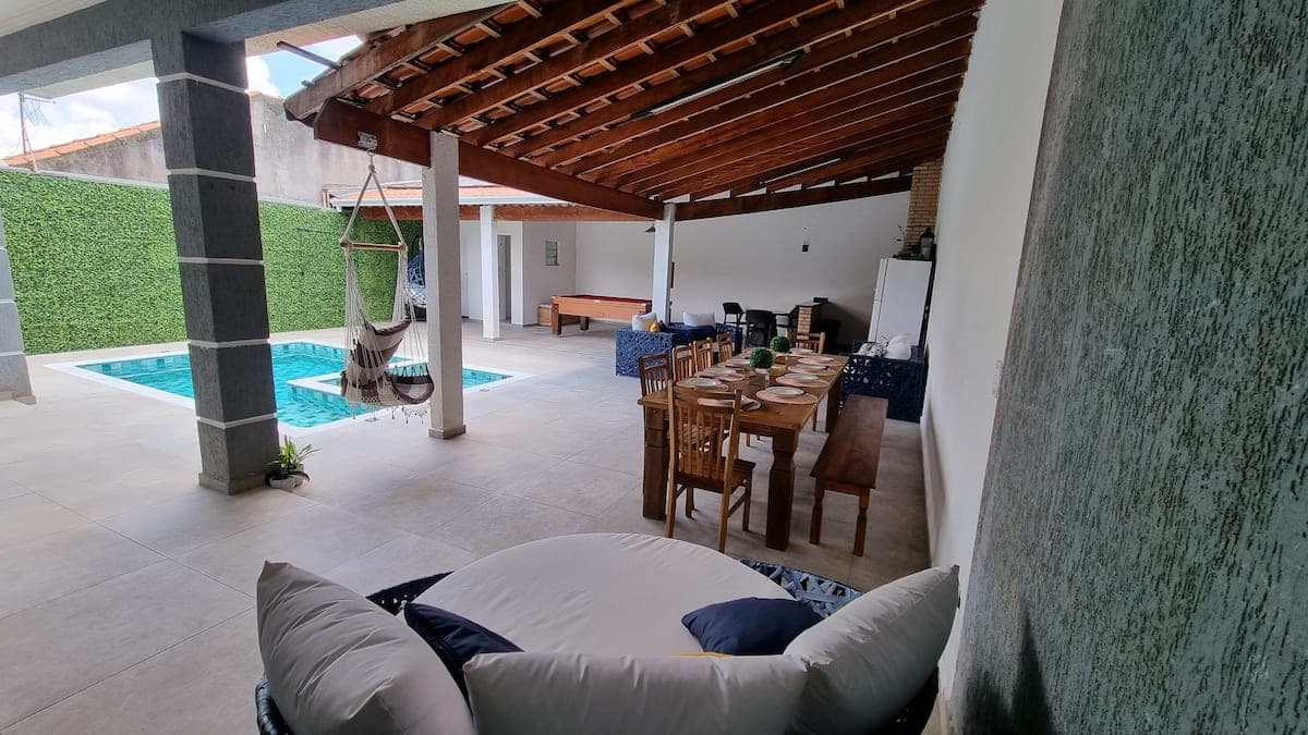 Varanda coberta com mesa de jantar e vista da piscina