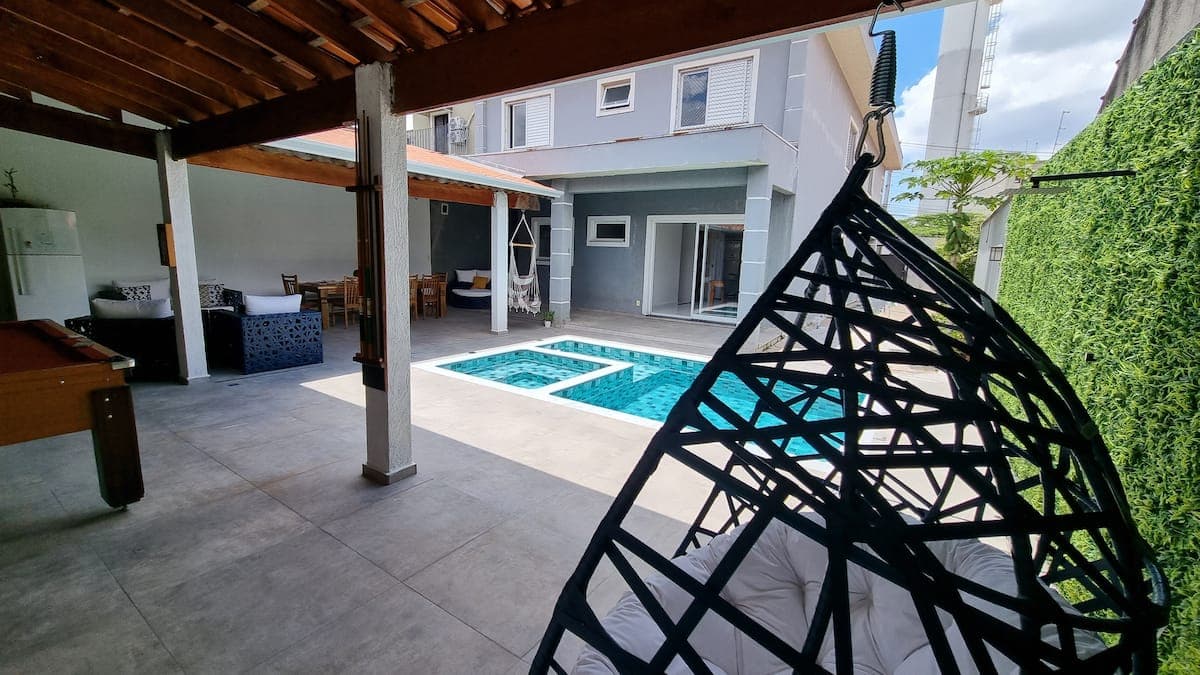 Area de lazer com cadeira suspensa ao lado da piscina