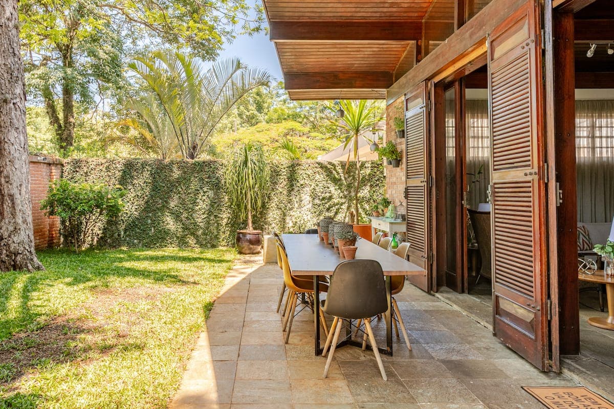 Jardim com gramado e mesa de refeicoes na varanda