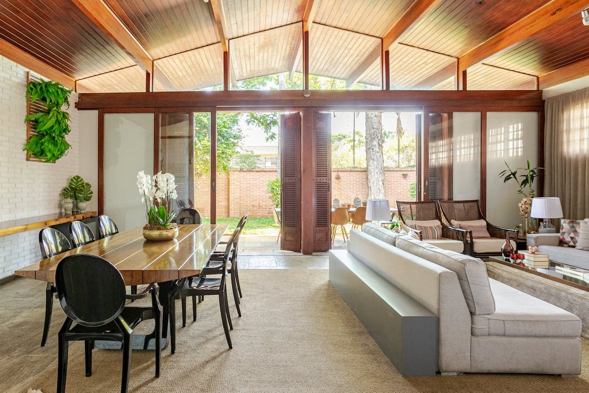 Sala de jantar aberta para o jardim, com teto de madeira