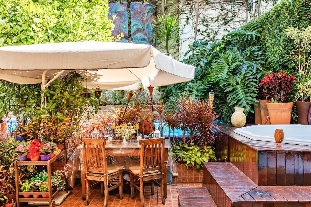 Deck com ombrelone, mesa de madeira, hidromassagem e jardim