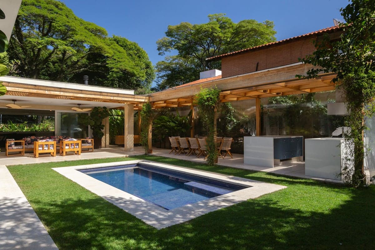 Piscina retangular com gramado e pergolado