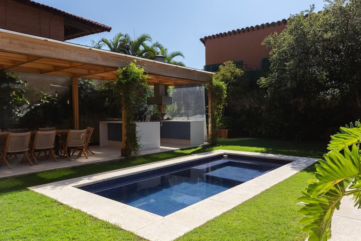 Piscina vista do pergolado, com vegetação ao redor