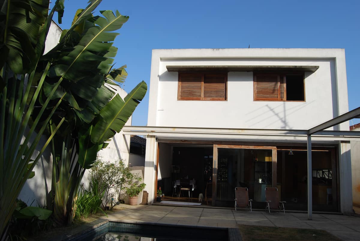 Fachada da casa com piscina e jardim de folhagens