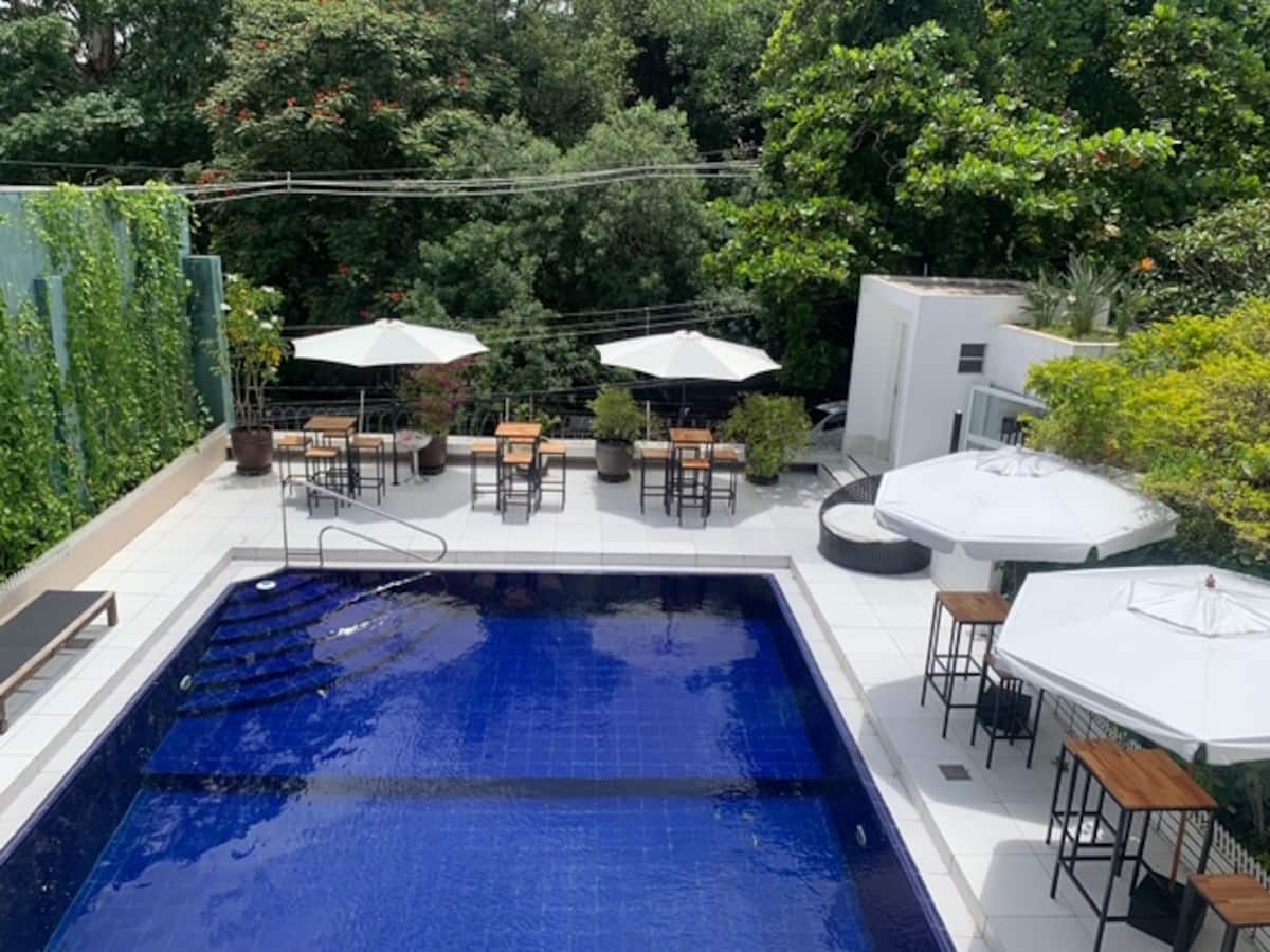 Piscina com guarda-sóis e mesas ao redor