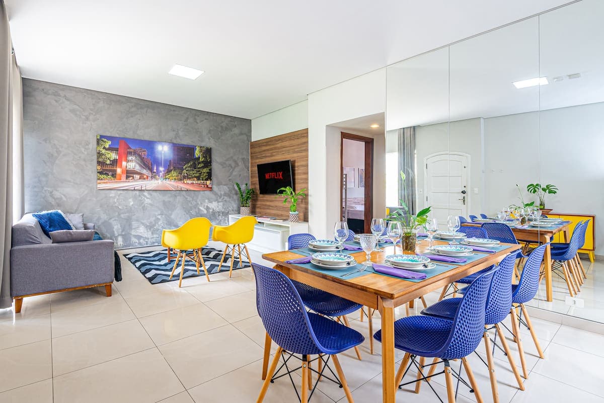 Sala de jantar com mesa posta e cadeiras coloridas