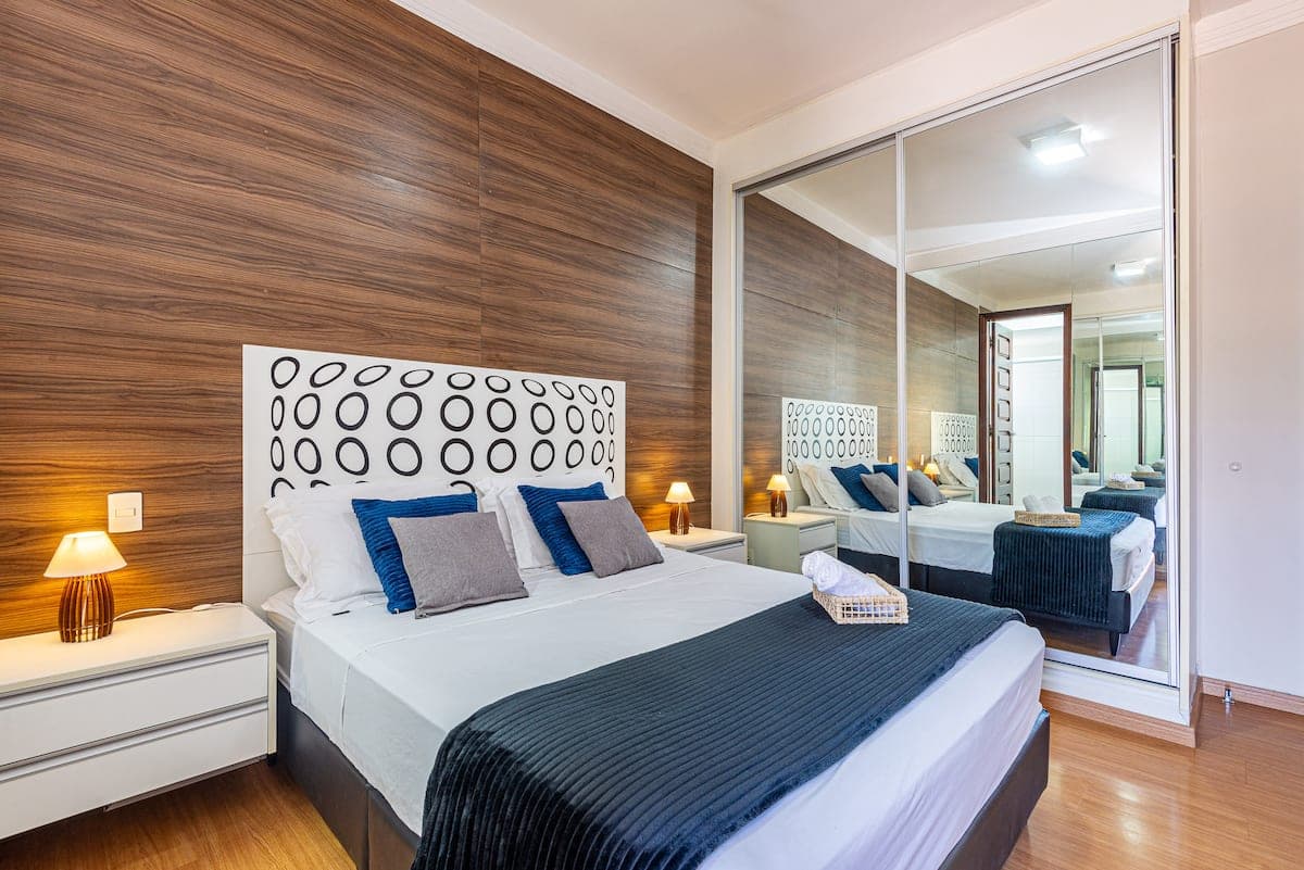 Quarto de casal com painel de madeira e armario espelhado