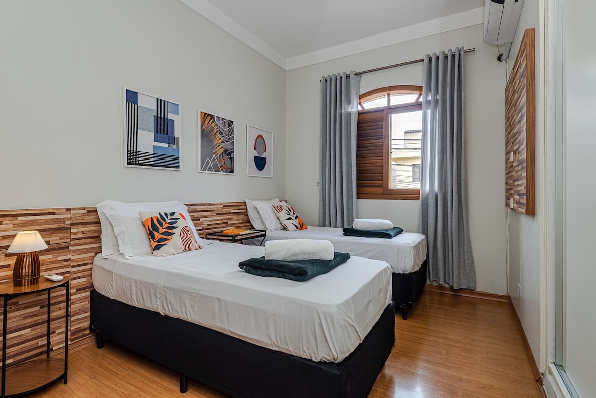 Quarto com duas camas de solteiro e janela