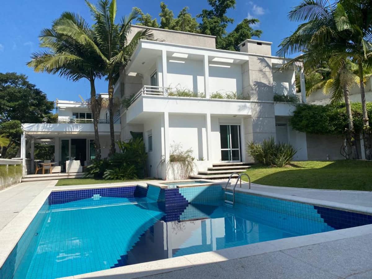 Piscina com palmeiras e a casa ao fundo