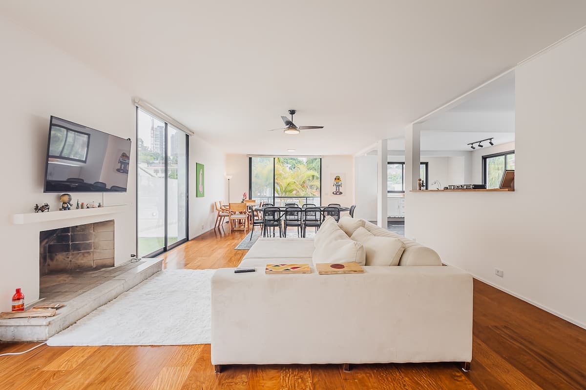Sala de estar integrada com lareira e sofa branco