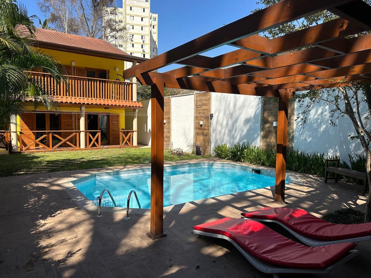 Piscina com pergolado de madeira e espreguiçadeiras