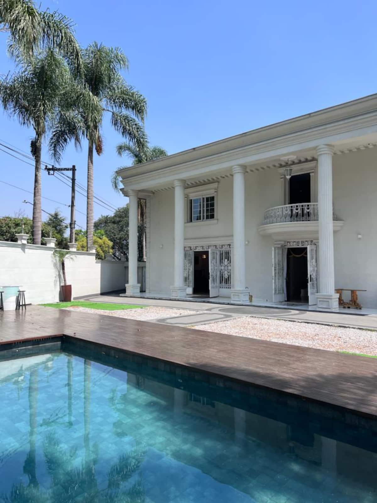 Fachada com colunas e piscina ao lado