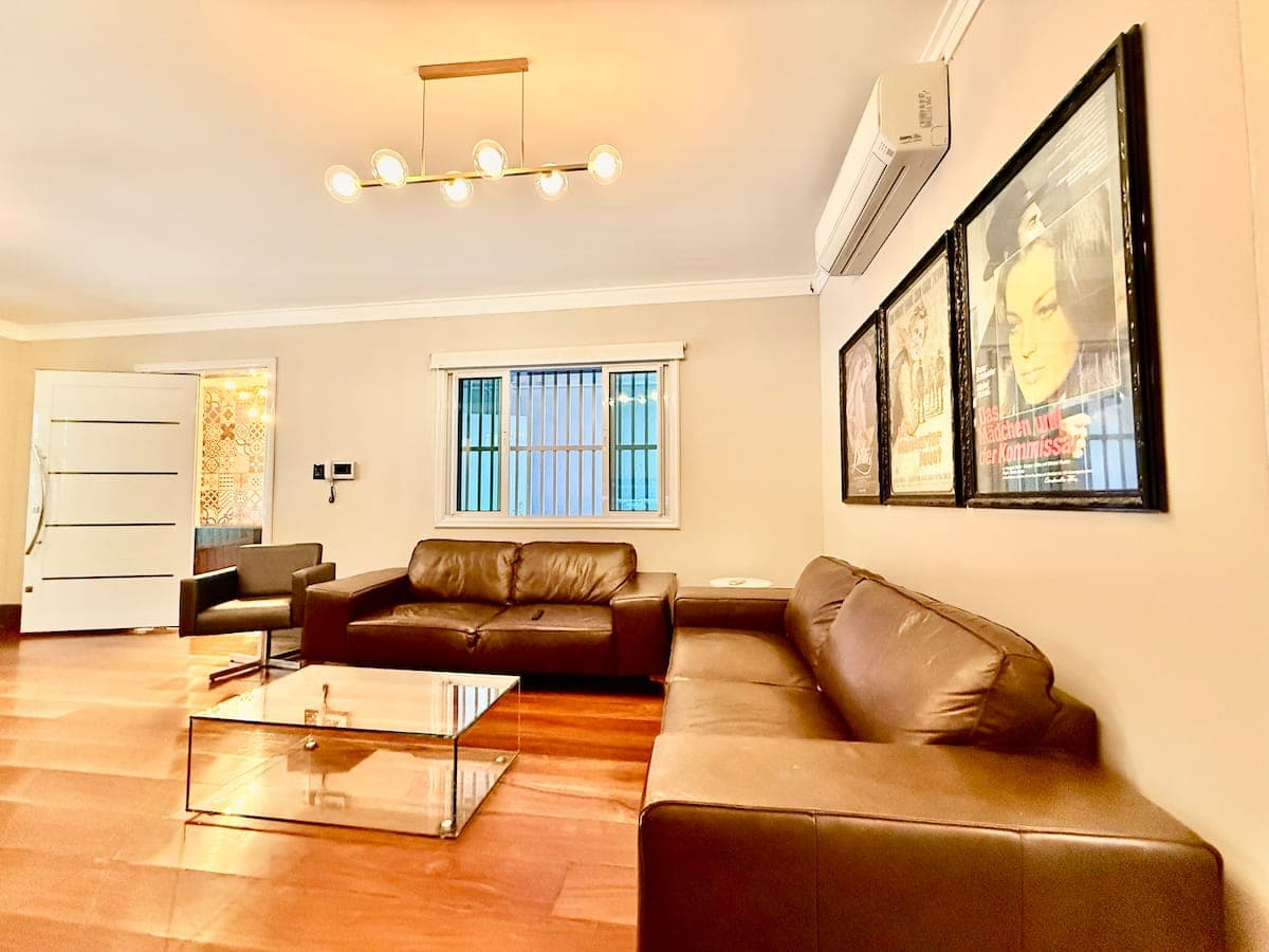 Sala com sofa em L, mesa de centro de vidro e quadros
