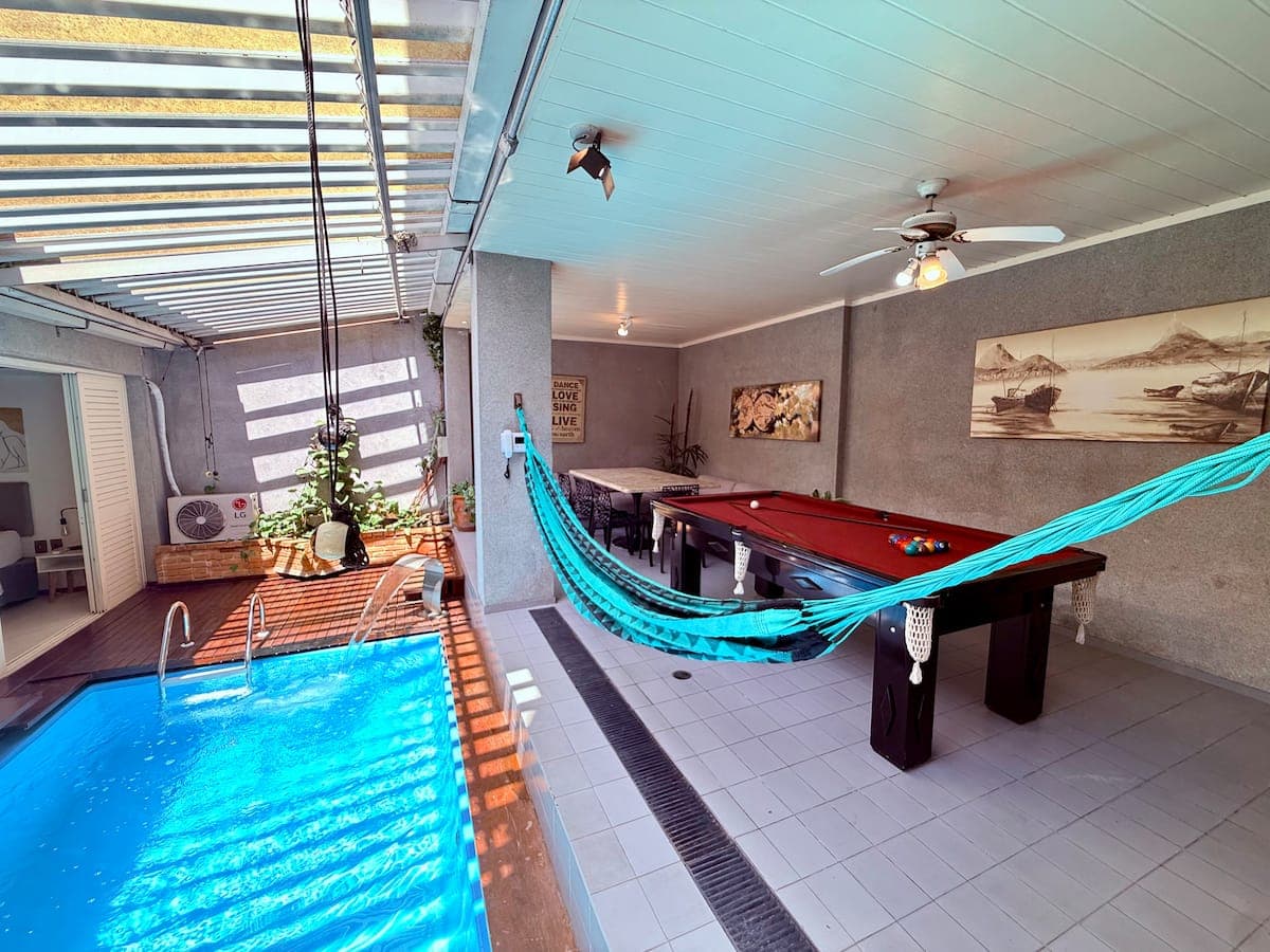 Piscina coberta com area de lazer, rede e mesa de sinuca