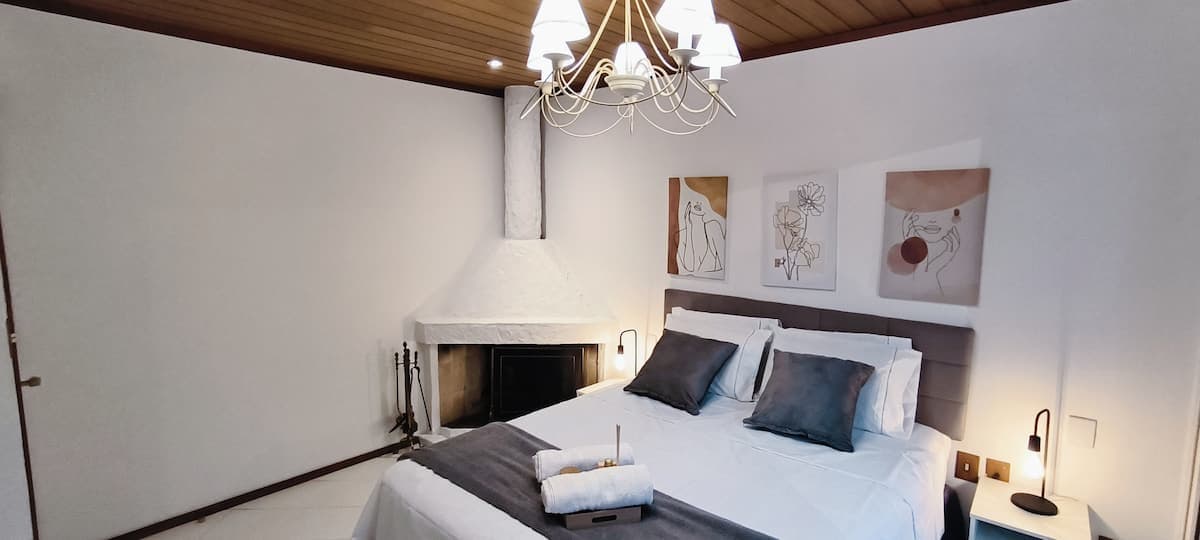 Quarto com cama de casal, lustre e teto de madeira